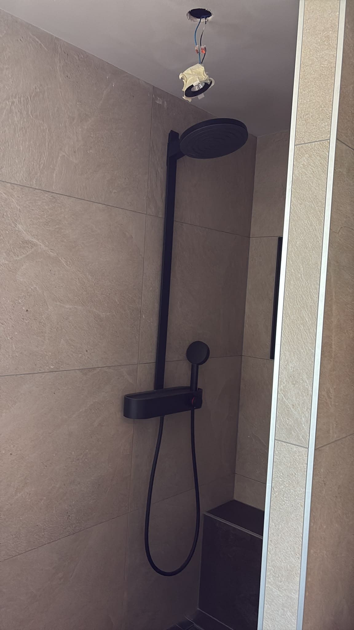 Afgewerkte douche met zwarte doucheset en plafond met spotopening